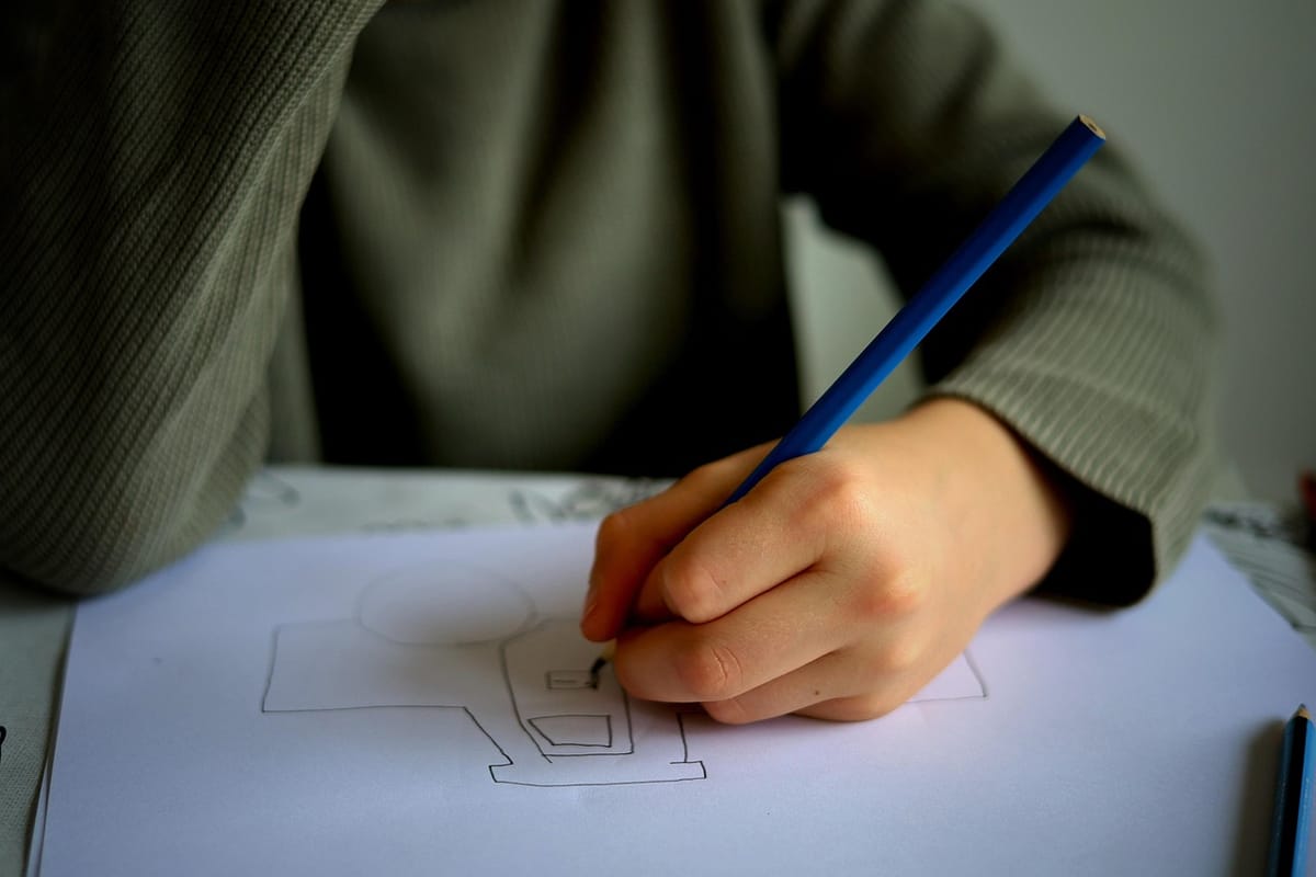 A picture of a child drawing a picture of a car on paper at a desk